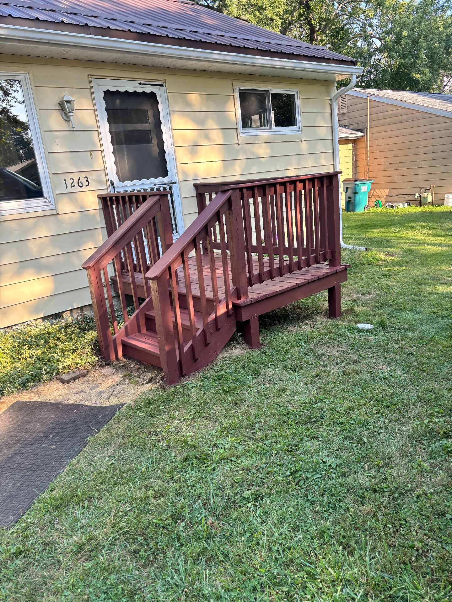 After: rebuilt porch and steps with new railings stained a deep redwood color