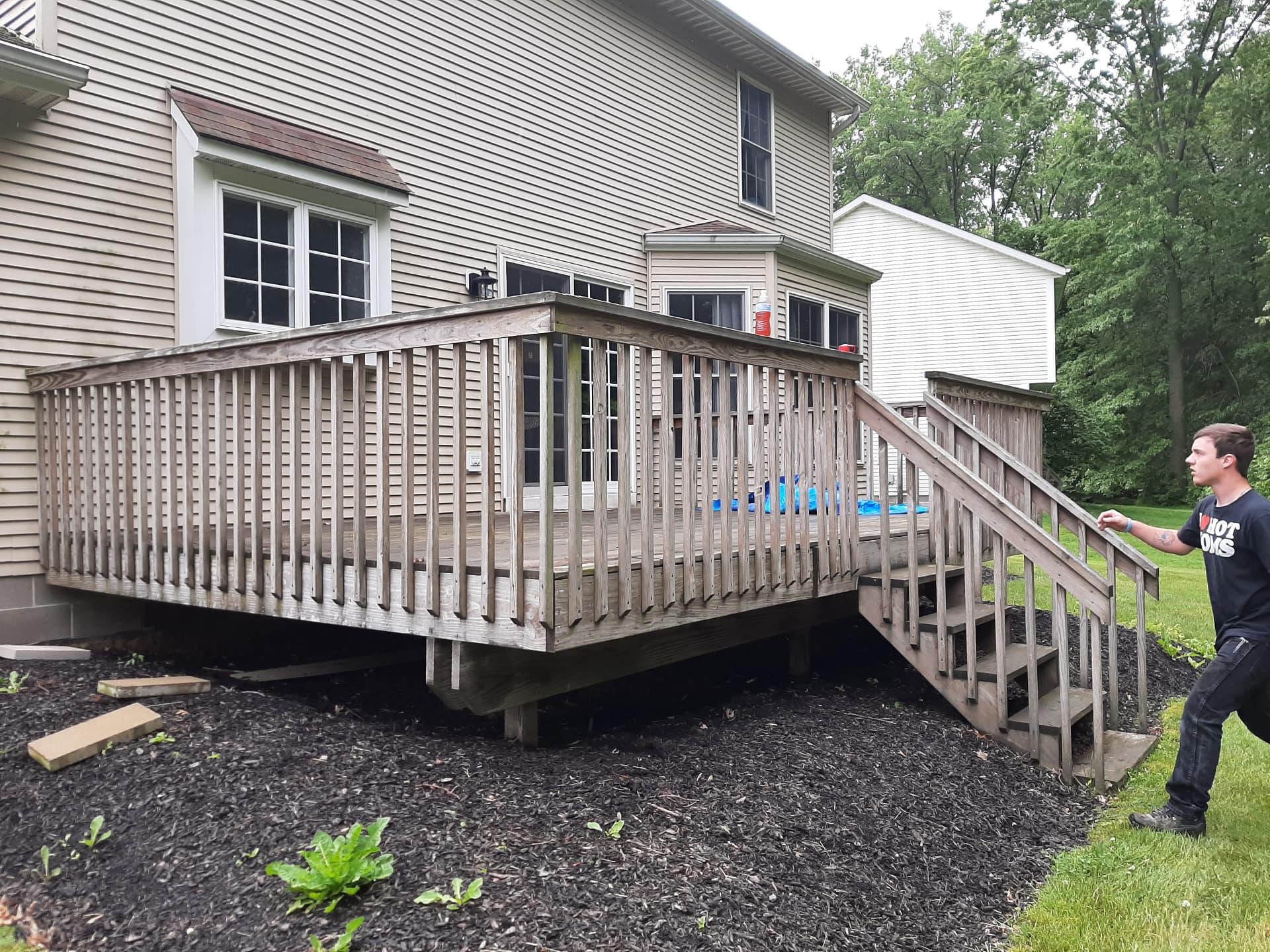 Before: weathered gray deck with faded railings behind a house