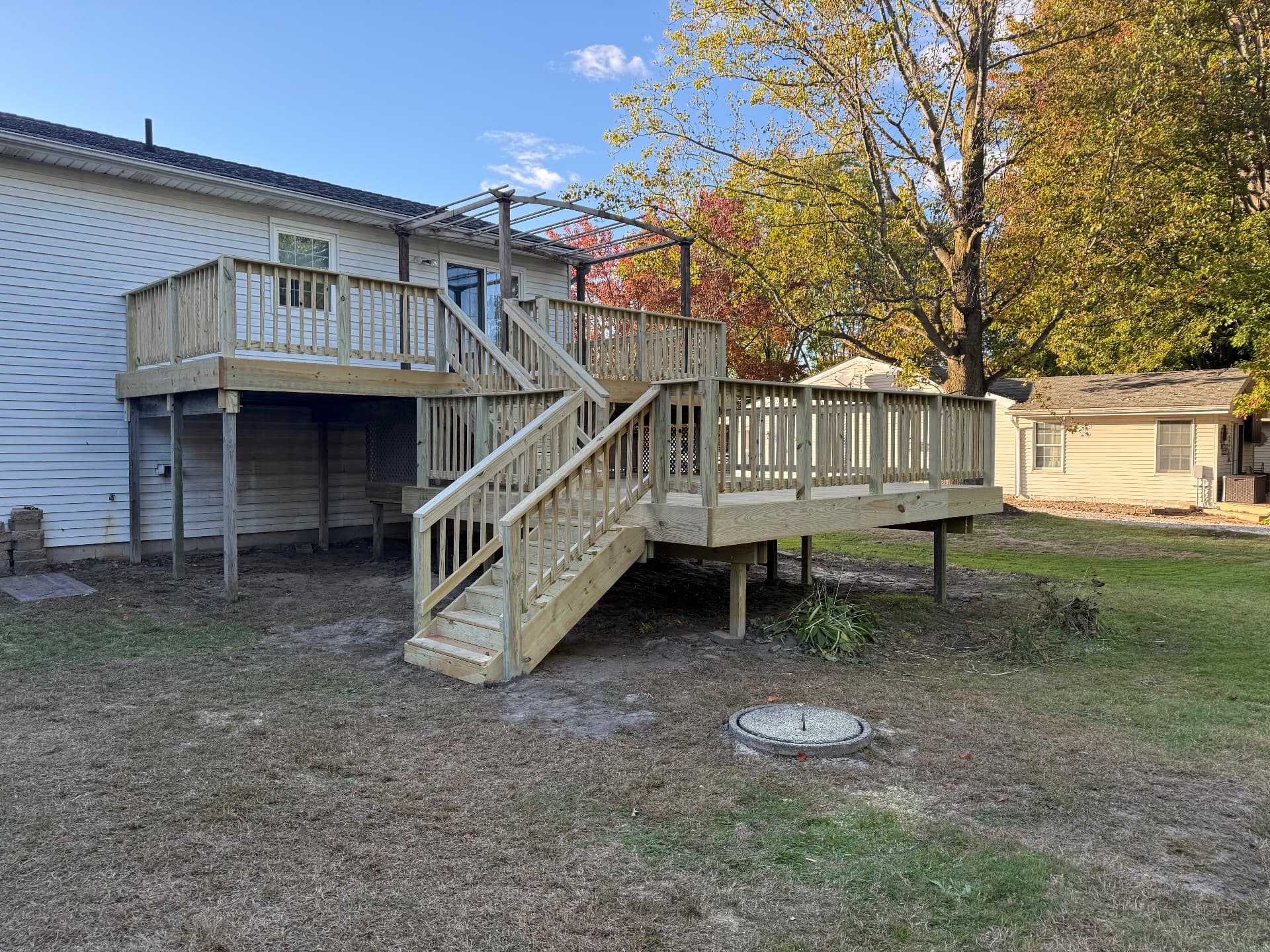 After: rebuilt two-level pressure-treated deck with new railings and pergola