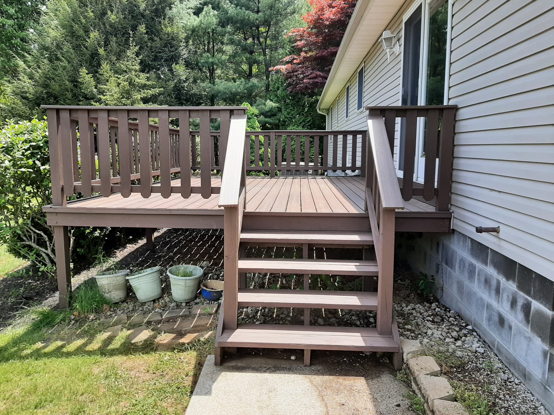 After: deck rebuilt with new framing, stairs and railings stained deep brown