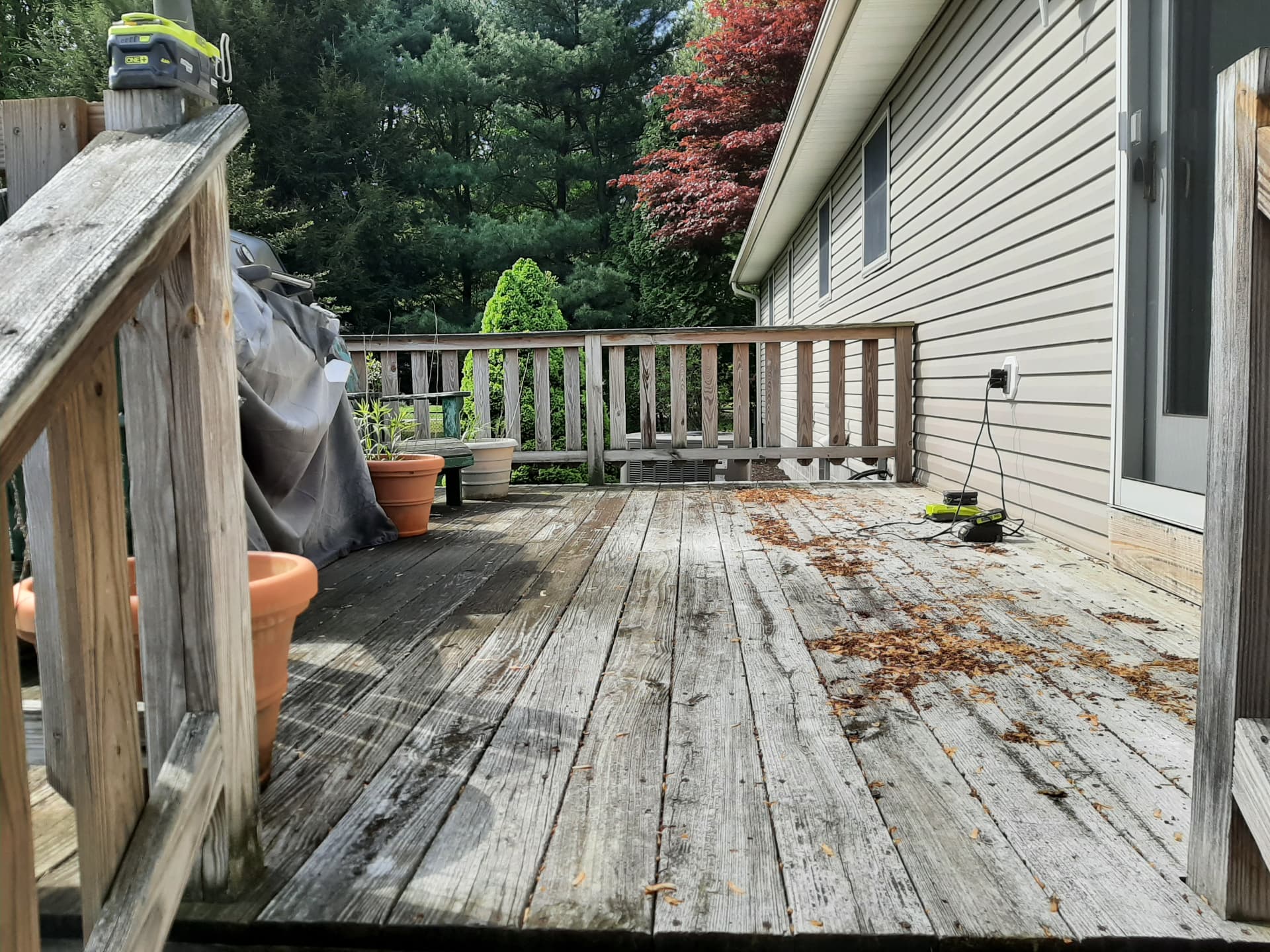 Before: weathered gray deck boards and faded railings behind a house